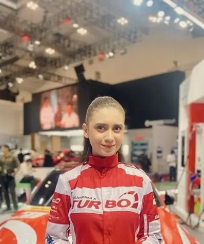 A brand ambassador in a red and white racing jacket at an auto show