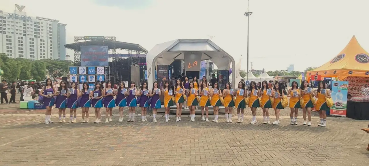 Tim besar brand ambassador berbaris dalam dua kelompok berseragam di depan panggung festival