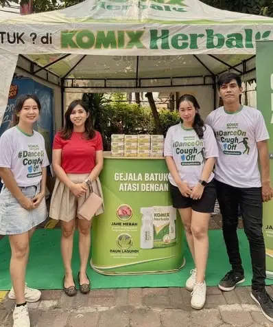 A booth team of four in front of an herbal product stand at an outdoor event
