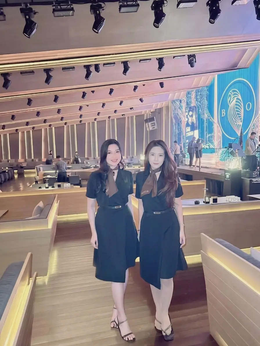Dua usher bergaun gelap dan syal senada di ruang acara